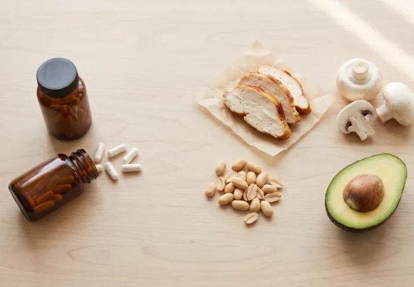 NMN vs niacinamide flat lay with unlabeled supplement bottles, capsules, chicken, peanuts, mushrooms and avocado