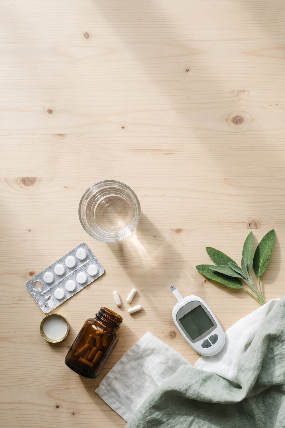 NMN with metformin pin: unlabeled supplement bottle, tablet strip and glucose meter flat lay